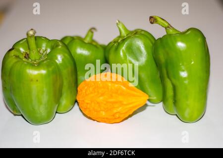 Gelbe bittere Kürbis zwischen grünen Paprika mit isoliertem Hintergrund, ungerade heraus Stockfoto