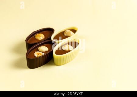 Schokolade Bonbons mit Mandeln und Haselnüssen auf gelbem Hintergrund. Stockfoto