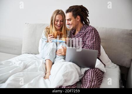 Liebevolles junges Paar beim Frühstück im Bett Stockfoto