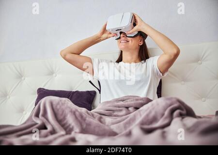Erwachsene Dame unterstützt die VR-Brille mit ihren Händen Stockfoto