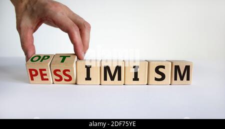 Symbol für Pessimismus oder Optimismus. Männliche Hand dreht Würfel und ändert das Wort "Pessimismus" zu "Optimismus". Schöner weißer Tisch, weißer Hintergrund. Unternehmen Stockfoto