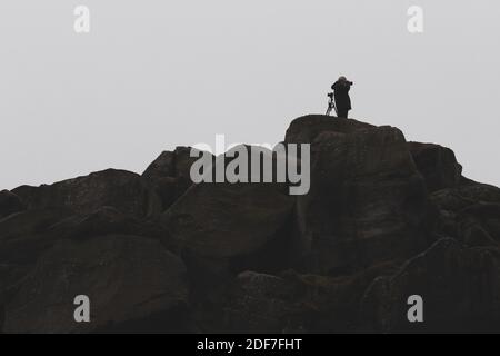 Person auf dem Land, die mit einer Kamera ein Foto macht, während seine andere Kamera auf einem Stativ steht und in die andere Richtung schaut, West Yorkshire Stockfoto
