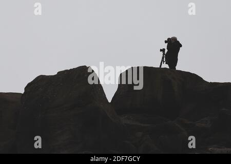 Person auf dem Land, die mit einer Kamera ein Foto macht, während seine andere Kamera auf einem Stativ steht und in die andere Richtung schaut, West Yorkshire Stockfoto
