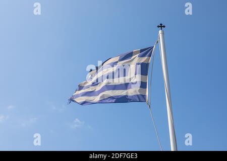 Flattern im Wind Flagge Griechenlands auf dem Mast. Blauer Himmel im Hintergrund. Ios-Insel, Griechenland. Stockfoto