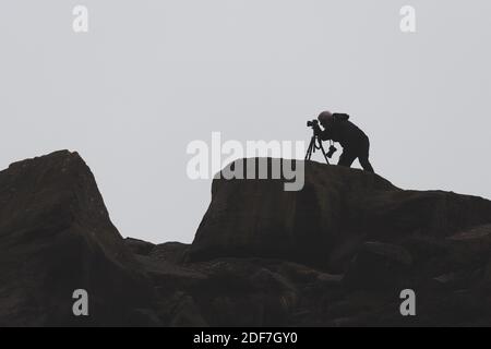 Person auf dem Land, die mit einer Kamera ein Foto macht, während seine andere Kamera auf einem Stativ steht und in die andere Richtung schaut, West Yorkshire Stockfoto