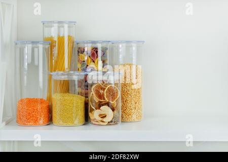 Sortiment von Getreideprodukten und Pasta in Glasbehältern auf weißem Holztisch. Gesundes Kochen, sauberes Essen, Null-Abfall-Konzept. Ausgeglichen Stockfoto