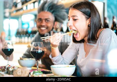 Glückliches Paar, das im Sushi-Bar-Restaurant eine Schüssel isst - Food Lifestyle-Konzept mit jungen Menschen Spaß zusammen an All you can eat Buffet Stockfoto