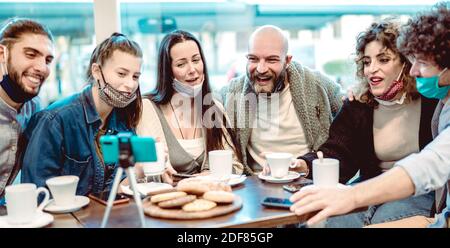 Junge glückliche Freunde teilen Inhalte auf Streaming-Plattform tragen Gesicht Maske - Neue normale Lifestyle-Konzept mit Millennial Jungs und Mädchen, die Spaß haben Stockfoto