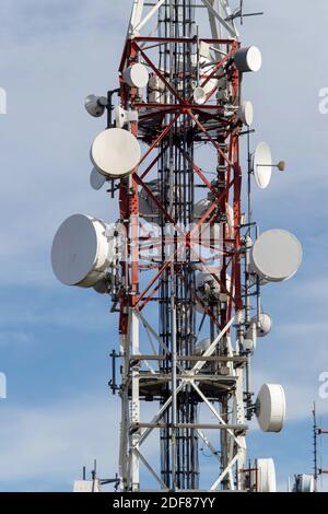 Rot-weißer Telekommunikationsturm mit Satellitenantennen und Kommunikationsgeräten. Stockfoto