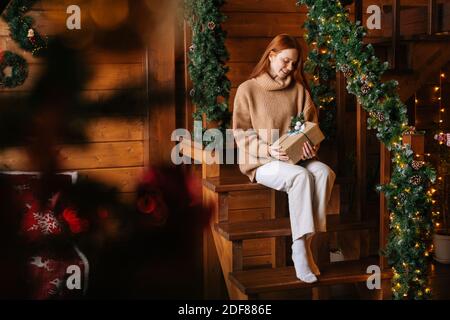 Porträt von charmanten jungen Frau Blick auf Kamera halten Geschenk Box in der Hand für Weihnachten erhalten Stockfoto