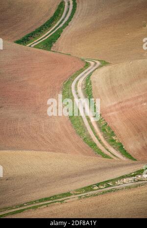 Kurvenreiche Straße durch trockene Landschaft mit leeren Feldern in Andalusien, Spanien Stockfoto