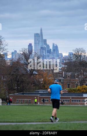 Ein älterer Mann, der im Brockwell Park mit dem Brockwell Lido und dem Londoner Stadtbild im Hintergrund läuft, London Stockfoto