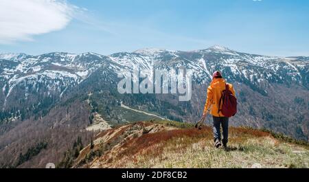 Gekleidet hell orange Jacke Backpacker Wandern durch Heidelbeer Feld mit Trekkingstöcken mit Bergkette Hintergrund, Slowakei. Aktive Menschen und die EU Stockfoto