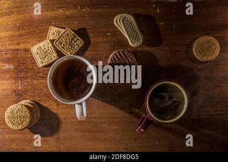 Blick von oben auf rustikalen Tisch mit dampfenden Tassen Tee und Keksen. Stockfoto