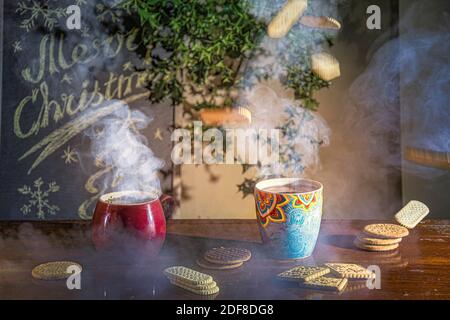 Weihnachten rustikalen Tisch mit dampfenden Tassen Tee, Kekse und Dekorationen Stockfoto