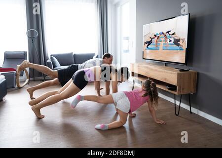 Familie tun Fitness-Übung beim Fernsehen Stockfoto