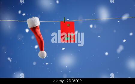 Weihnachtsmütze und rote Plastikkarte mit Neujahr-Design An einer Schnur hängen Stockfoto