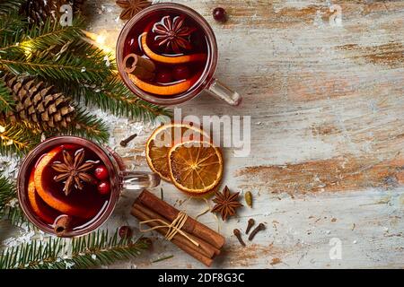Glühwein mit Gewürzen und Weihnachtsbeleuchtung Stockfoto