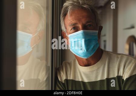 Porträt eines älteren kaukasischen Mannes mit Gesichtsmaske zu Hause Stockfoto