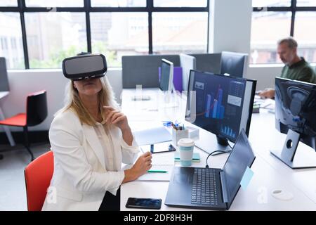 Kaukasische Frau, die im kreativen Büro arbeitet und ein vr-Headset trägt Stockfoto
