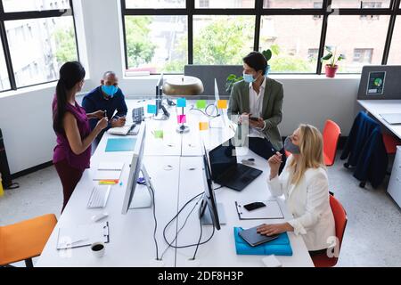 Vielfältiges Team trägt Gesichtsmasken Brainstorming im kreativen Büro Stockfoto