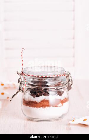 Weihnachtsgeschenk Cookie-Mix in Glas auf Holztisch. Schichten von Mehl, Kakaopulver, Zucker. Zutaten für Ingwerbrot. Platz für Text kopieren Stockfoto