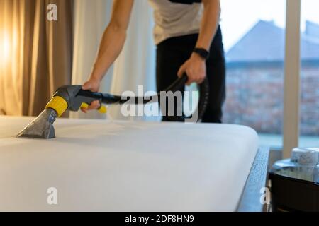 Reinigungsverfahren für Matratzen. Mann reinigt Bett von Schmutz und Bakterien Stockfoto