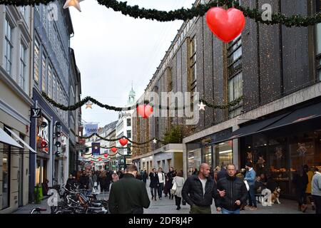 Købmagergade, eine geschäftige Straße voller Geschäfte und Einkäufer in Kopenhagen, Dänemark. Weihnachtsdekorationen und Lichter hängen über der Straße. Stockfoto