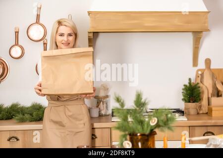 Frau mit einem Paket von Lebensmitteln Lieferung. Arbeiter, der während der Coronavirus-Periode Lieferkost in der Backstube zubereitet Stockfoto