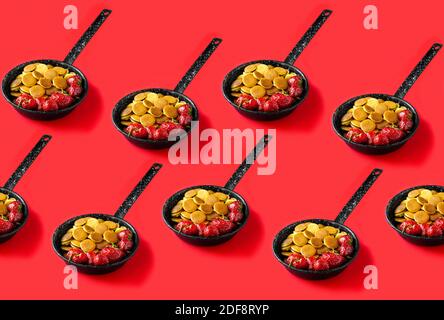 Trendiges Essen - Pfannkuchen Müsli. Nahtloses Muster aus Mini-Cerealien-Pfannkuchen mit Erdbeeren in einer Pfanne auf rotem Hintergrund Stockfoto