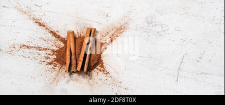 Nahaufnahme Detail - Zimtrinde und gefrästes Pulver auf weißem Steinbrett, Ansicht von oben, Platz für Text rechts Stockfoto
