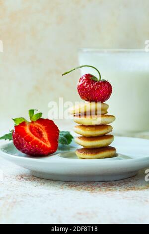 Trendiges Essen - Pfannkuchen Müsli. Stapel von Mini-Cerealien-Pfannkuchen mit Erdbeeren und Milch Stockfoto