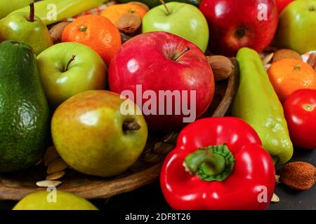 Gemischte Früchte - Äpfel, Birnen, Mandarinen; und Gemüse - Paprika, Tomaten, Avocados; mit einigen ganzen Mandeln und Nüssen, Nahaufnahme Stockfoto