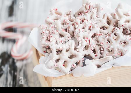 Hausgemachte weiße Schokolade oder Joghurt bedeckt Brezeln mit Stücken von zerkleinerten Zuckerrohr. Selektiver Fokus mit verschwommenem Vorder- und Hintergrund. Herz s Stockfoto