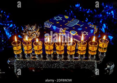 Nahaufnahme der Menora mit Kerzen für Chanukka und Geschenkbox auf dem Hintergrund. Jüdischer Feiertag. Stockfoto