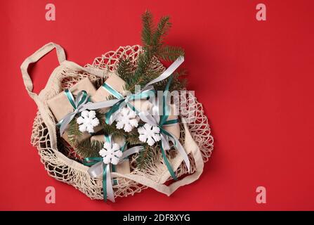 Weihnachten Zero Waste Dekor und Geschenkboxen aus Kraftpapier in beige Baumwolle Öko-Tasche auf rot. Flach liegend. Speicherplatz kopieren Stockfoto