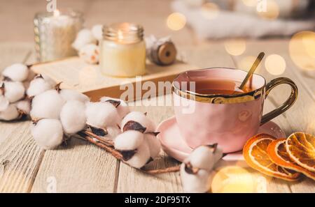 Details des Stilllebens im Wohnzimmer. Pullover, Tasse Tee, Baumwolle, gemütlich, Buch, Kerze. Moody. Gemütliches Winter-Konzept im Herbst. Dekoration Stockfoto