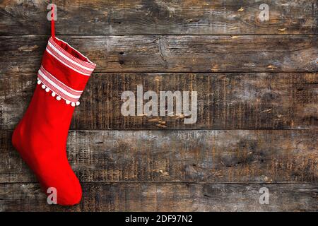 Roter Weihnachtsstrumpf auf Holzhintergrund. Rustikale verwitterte Oberfläche Stockfoto