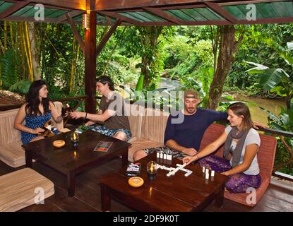 Die Gäste genießen die obere Bar und das Restaurant in UNSEREM DSCHUNGELHAUS eine Lodge im Regenwald in der Nähe VON KHAO SOK NATIONALPARK - SURATHANI PROVENCE, THAILAND Stockfoto