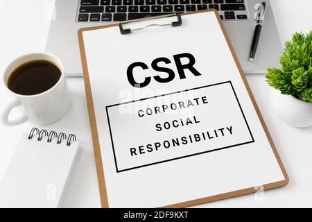 CSR Corporate Social Responsibility auf einem Whitepaper, das auf dem Laptop-Computer platziert ist. Stockfoto