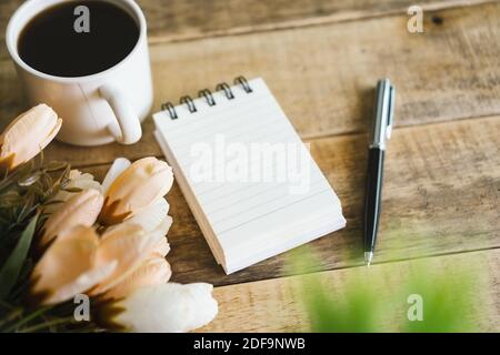 Kleiner Spiralnotepad und Kaffee auf rustikalem Holz. Stockfoto