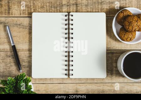 Notizbuch, Kekse und Tasse Kaffee auf rustikalem Holz. Flach liegend mit Platz für Textkopien. Stockfoto