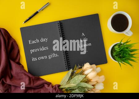 Notizbuch mit Weisheitszitat und Kaffeetasse auf gelbem Hintergrund. Stockfoto
