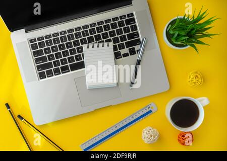 Laptop und kleines Notebook auf gelbem Schreibtisch. Elegante flache Arbeitsfläche. Stockfoto