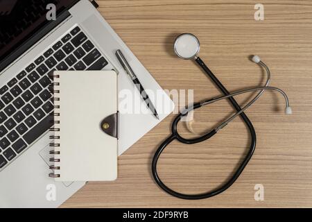 Stethoskop mit Notebook und Laptop auf Holzhintergrund. Arbeitsplatz für Ärzte. Stockfoto