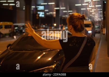Frau, die nachts auf einem Flughafen ein Taxi holte. Stockfoto