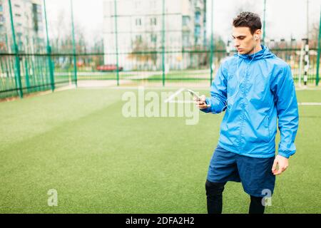 Ein junger Mann spielt Sport, läuft auf dem Fußballplatz. Der Typ arbeitet an der frischen Luft. Isolierte Stelle für Text Stockfoto