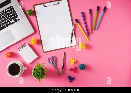 Bürobedarf, Laptop und Kaffee auf rosa Hintergrund. Bunte und lebendige Bürotisch Stillleben. Stockfoto