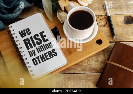 Inspirierende und Motivation Leben Zitat auf Merkzettel - Wir erheben uns, indem wir andere heben. Stockfoto