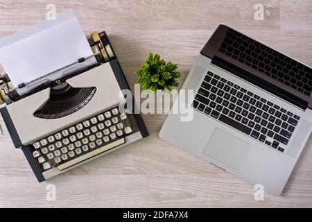 Ansicht von oben auf alte Schreibmaschine mit Papierbogen und Laptop Seite an Seite. Stockfoto